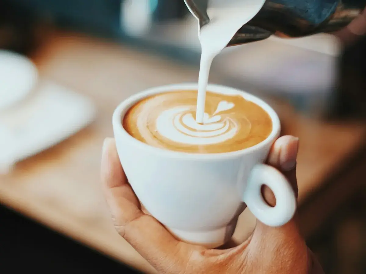 Barista pouring milk into a cup